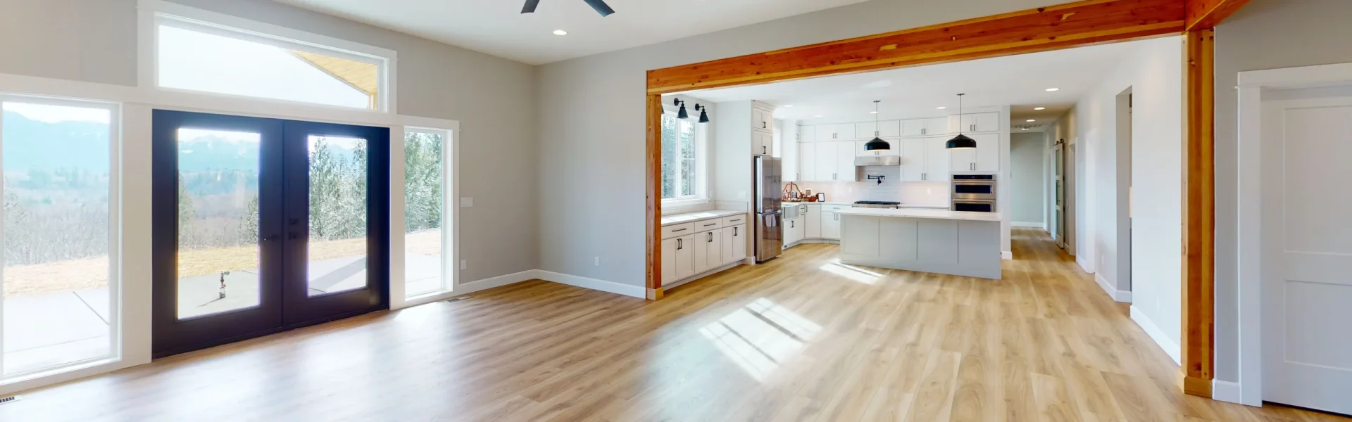 Photo of large living room with ceiling fan and wood beam accents