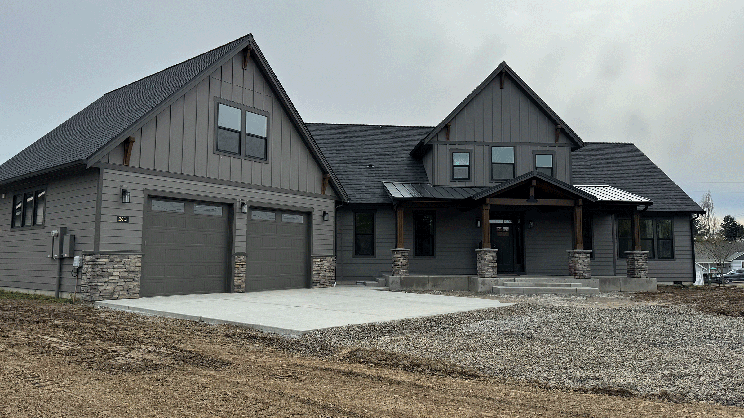 Photo of a custom home with unfinished driveway and landscaping